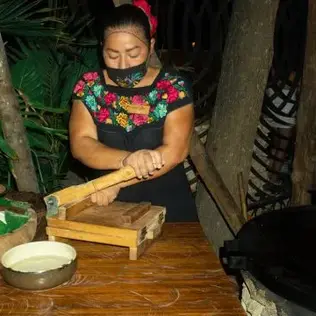 Mujer preparando tortillas a mano con una prensa tradicional en Mamazzita