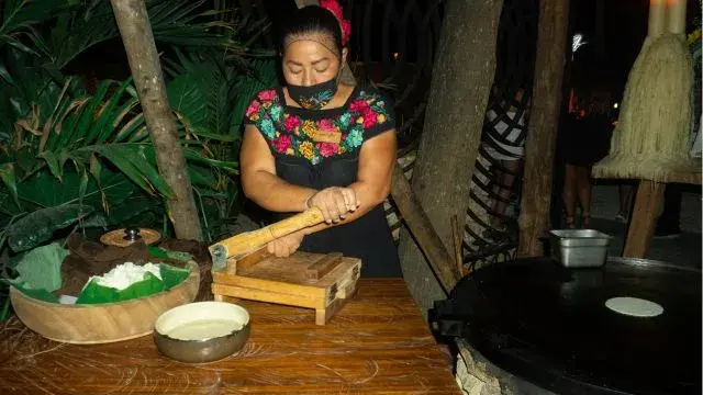 Mujer preparando tortillas a mano con una prensa tradicional en Mamazzita